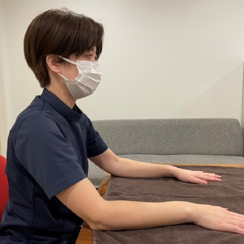 椅子に座り、両腕を肩幅に広げ、両手のひらをテーブルに置きます。