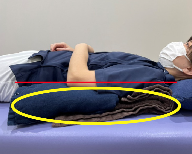 肩と肘が同じ高さ（赤線）になるように、黄色の丸の部分にクッションやバスタオルを置きます。肩甲骨の下にも置くことで、安定性を高めることができます。