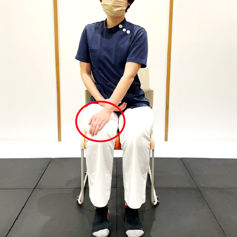椅子に座ります。片側の手を反対側の膝に置きます。